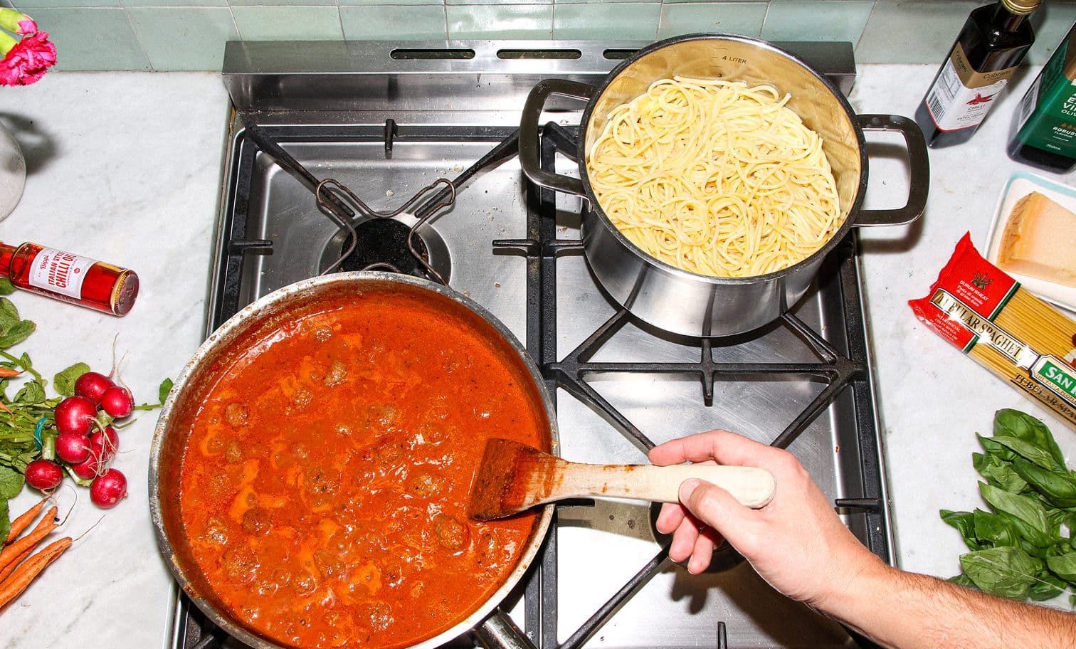 Kitchen counter with pasta, radishes, herbs and cooking sauce